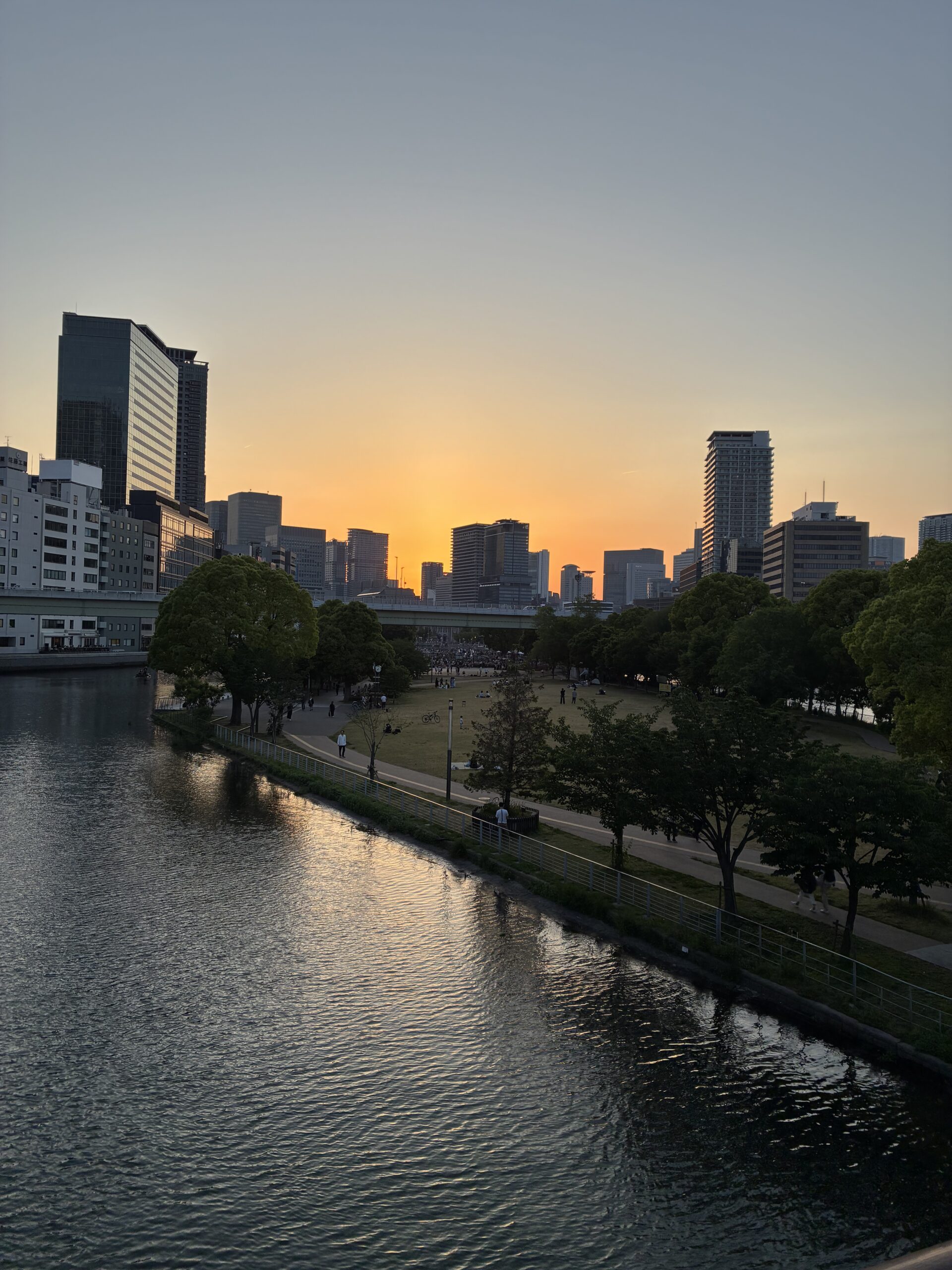 五月の夕暮れ、川沿いに広がる橙色の空と都会のシルエット